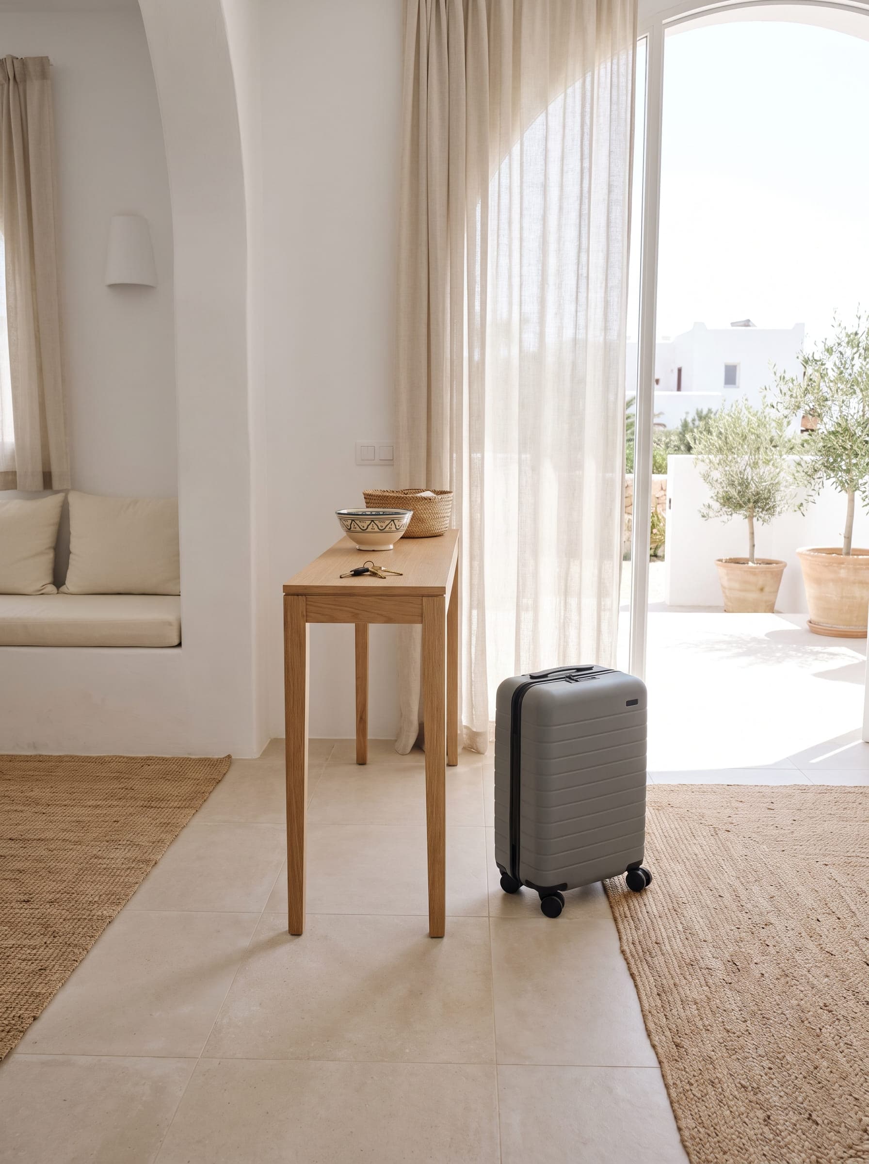 A guest's suitcase set down inside the sunlit entrance of a modern holiday rental