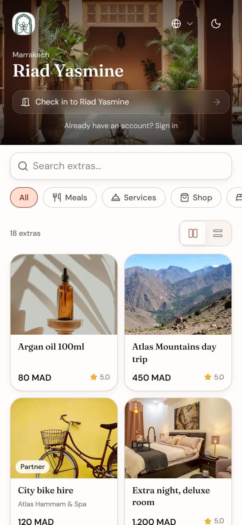 A guest storefront on a phone: the property name, then its extras with photographs and prices in dirham, including one supplied by a partner business